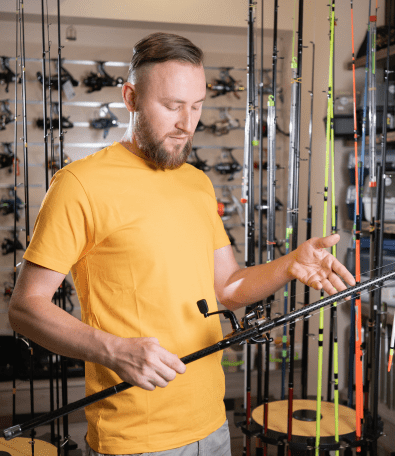 Man examining fishing rod in store.